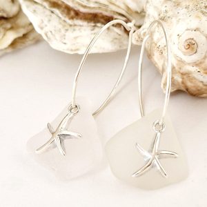 Ocean Start Hoop Earrings presented next to eachother and with sea shells in the background