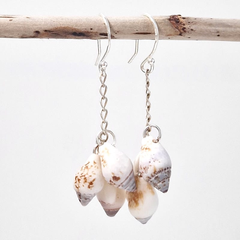 Cora Sea Shell Dangling Earrings hanging on wooden stick