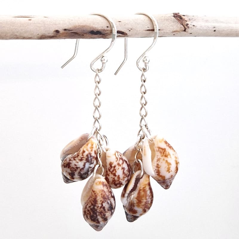 Sereia Sea Shell Dangling Earrings hanging on wooden stick